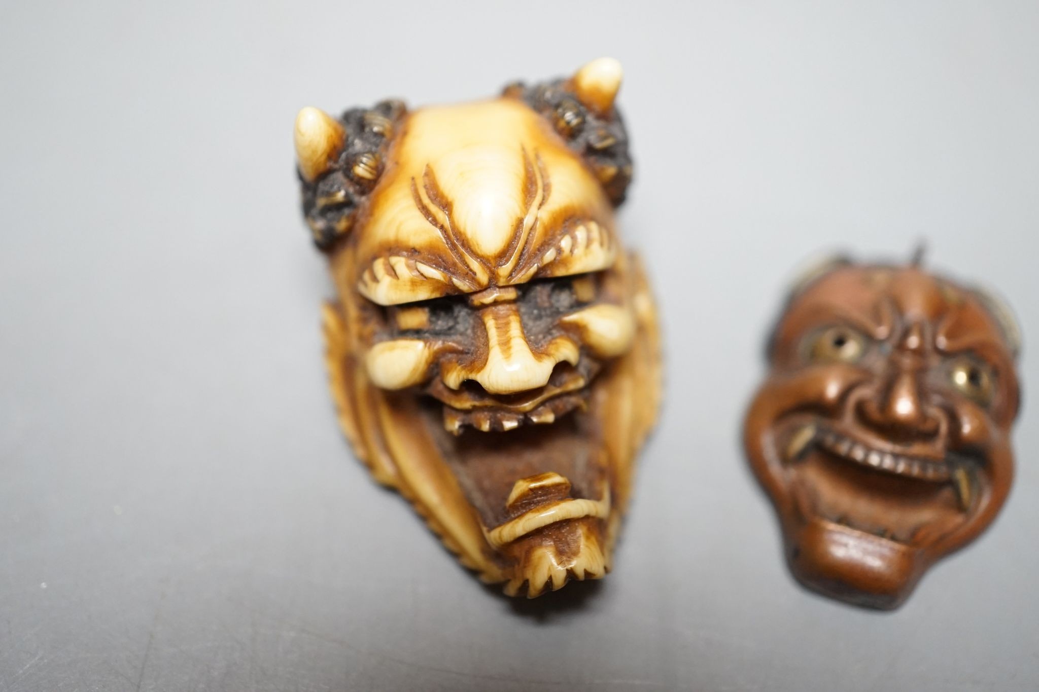 An unusual Japanese mixed metal noh mask containing minute bone dice and a stag antler noh mask brooch, signed, 3.5cm